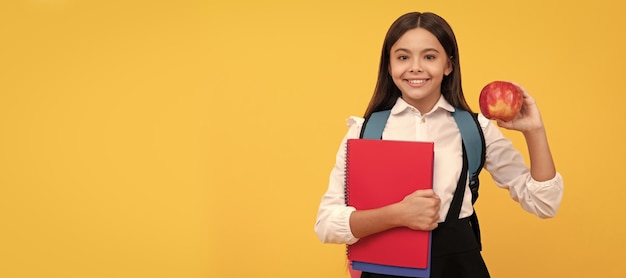 Garoto feliz volta para a escola segurando maçã e livros dia de conhecimento de fundo amarelo Retrato de cabeçalho de banner de estúdio de estudante colegial copyspace de rosto de criança em idade escolar