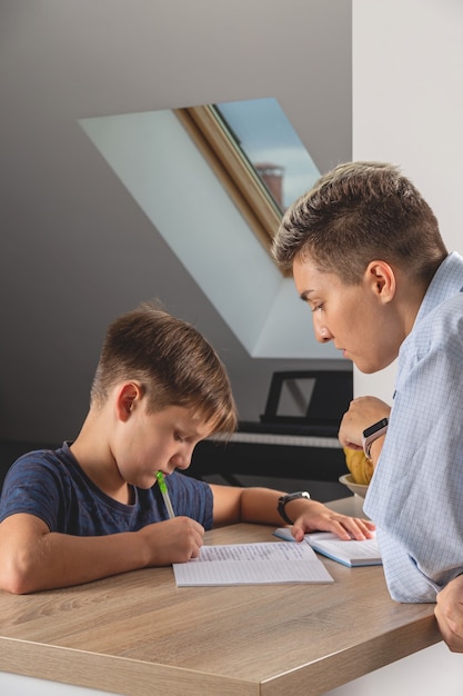 Garoto garoto fazendo lição de casa na mesa da cozinha com um livro