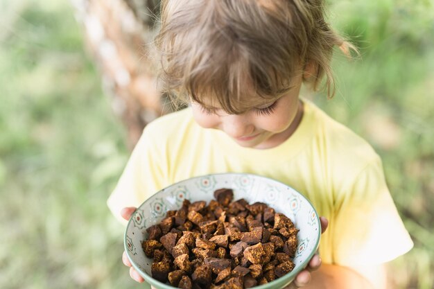 Garoto garoto feliz mãos segurando um prato com pedaços de chaga limpos e fatiados. cogumelo chaga forrageado fungo da bétula selvagem é usado na medicina alternativa para preparar chá curativo para o tratamento covid-19