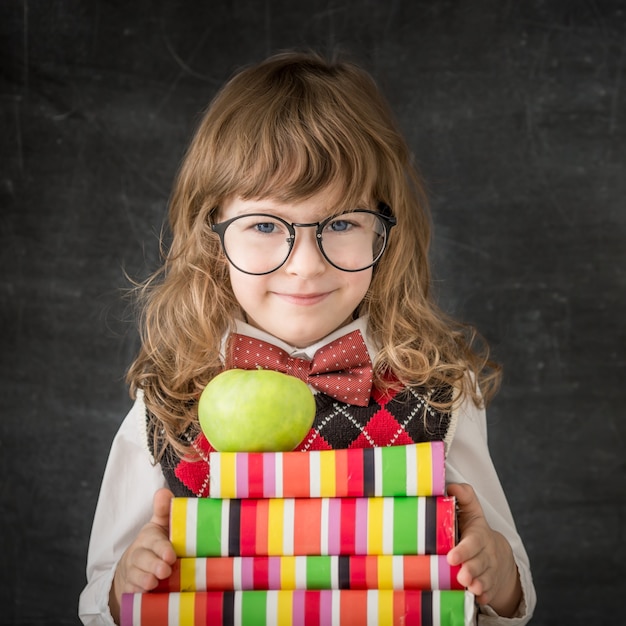 Garoto inteligente na aula. Criança feliz contra o quadro-negro. Conceito de educação