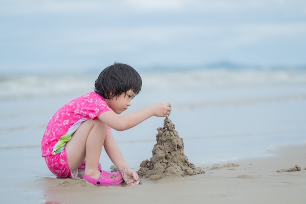 garoto jogando areia na praia, crianças brincando no mar