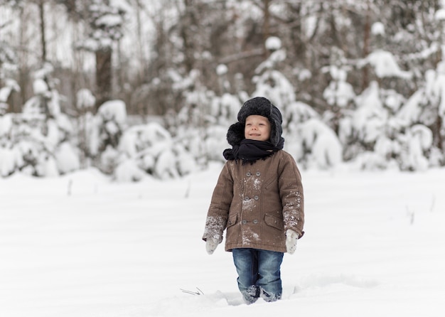 garoto jogando bolas de neve no inverno na natureza