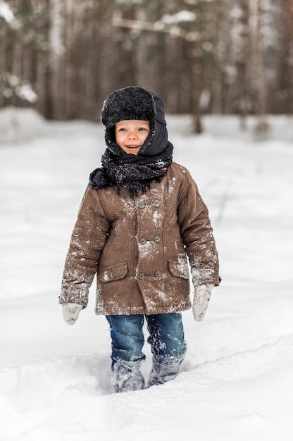 garoto jogando bolas de neve no inverno na natureza