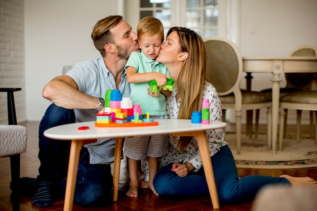 Garoto jogando brinquedos com a mãe e o pai em casa