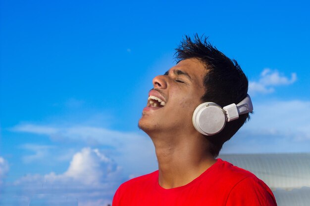 Garoto jovem adolescente bonito ouvindo música com fones de ouvido em emoções de humor relaxado