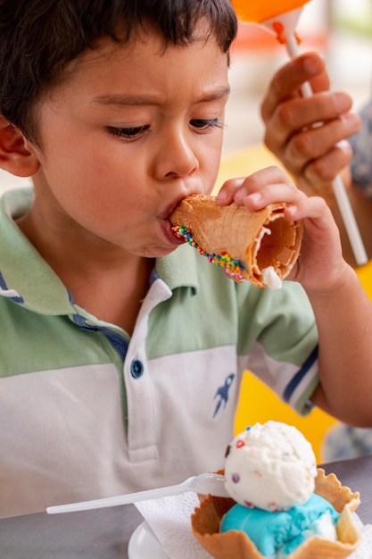 Garoto latino comendo um sorvete de maneira engraçada Sorvete com biscoito para crianças