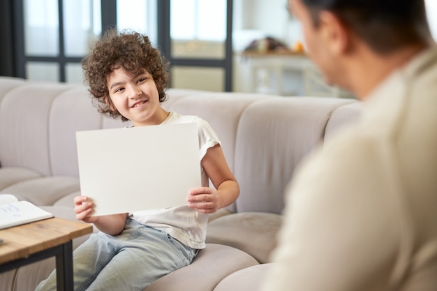 Foto garoto latino feliz mostrando o desenho para seu pai enquanto passa um tempo com seu pai