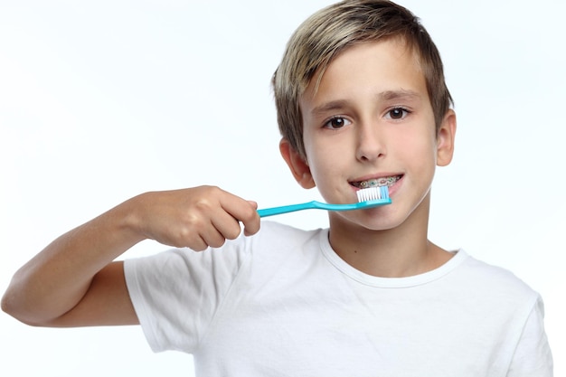Foto garoto limpando os dentes sobre fundo branco