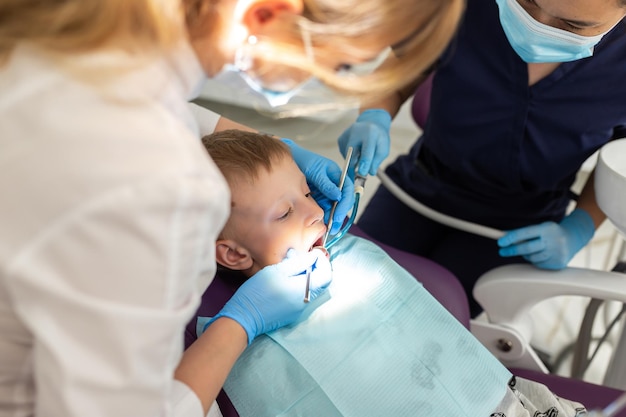 Garoto lindo na cadeira do dentista o escritório trata os dentes