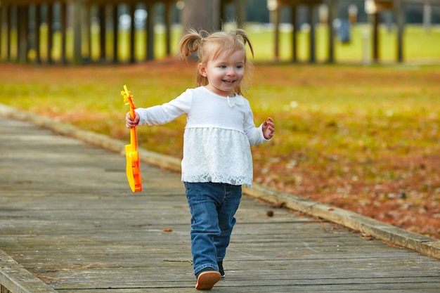 Garoto menina com guitarra de brinquedo andando no parque