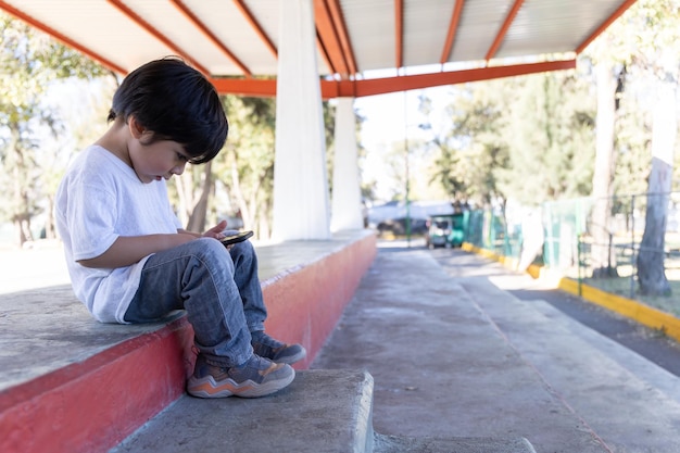 Garoto mexicano brincando com dispositivos móveis ao ar livre