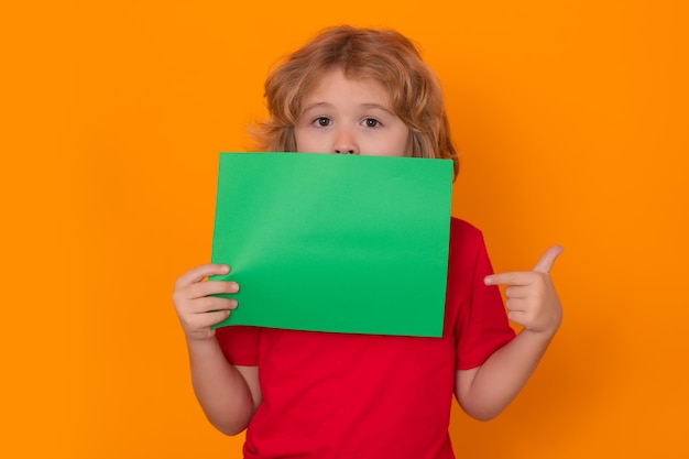 Garoto mostrando um banner verde em branco no cartaz de publicidade de fundo amarelo, ponto de criança no emp