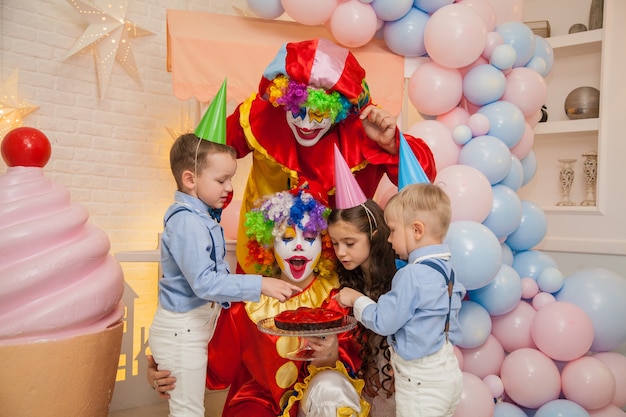 Garoto palhaço e garota palhaço em uma festa infantil soprando as velas do bolo