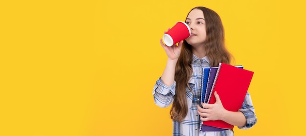 Garoto positivo em camisa quadriculada com pasta de trabalho bebendo café da xícara Retrato de cabeçalho de banner de estúdio de estudante colegial copyspace de rosto de criança de escola