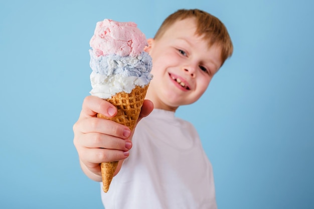 Garoto positivo segurando sorvete em um fundo azul Conceito de sorvete de benefícios para a saúde