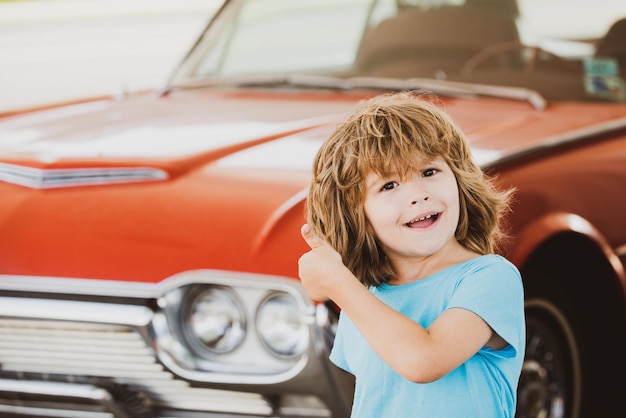 Garoto reabastecer o posto de gasolina do carro menino feliz contra automóvel retro vermelho