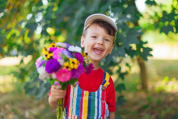 Garoto rindo com um buquê de flores uma criança com um buquê de flores silvestres para a mãe um presente surpresa ...