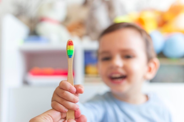 Garoto rindo pegando uma escova de dentes de arco-íris da mão do pai