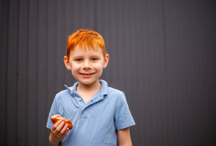 Foto garoto ruivo comendo um pãozinho