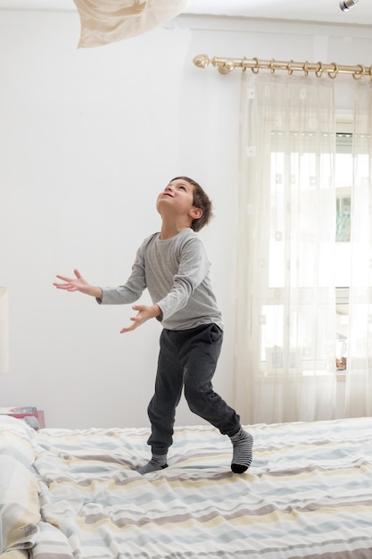 Garoto se divertindo no quarto na cama