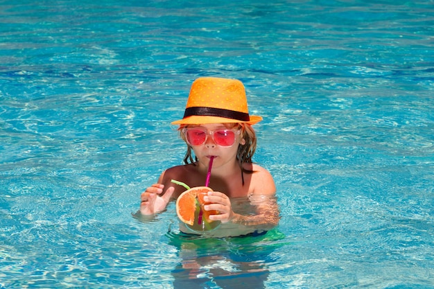 Garoto segura suco de frutas e legumes saudáveis na piscina de verão criança feliz desfrutando de organi