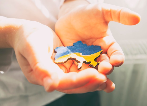 Garoto segurando a forma de madeira da Ucrânia colorida em cores nacionais na mão