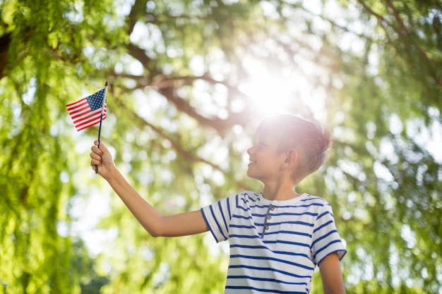 Garoto segurando pequena bandeira americana no parque
