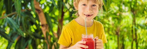 Garoto segurando smoothie de melancia saudável em formato longo de banner de mason jar