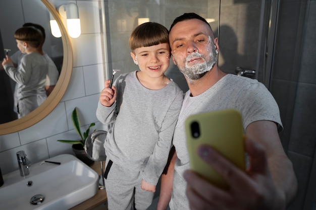 Garoto sorridente de alto ângulo e pai tirando selfie