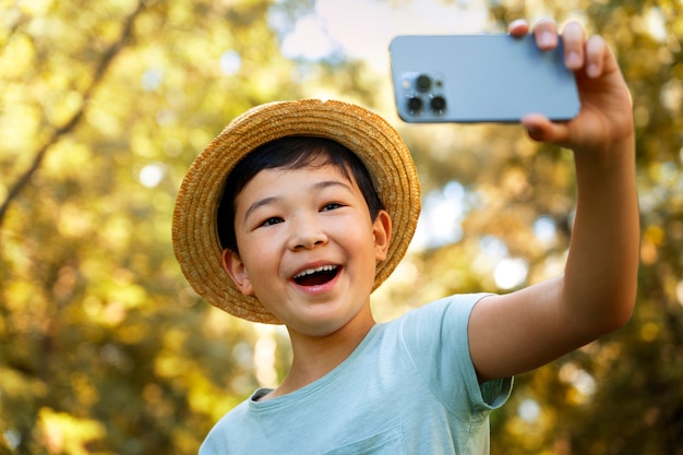 Garoto sorridente tirando selfie em ângulo baixo