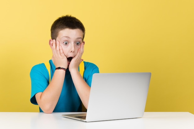 Garoto surpreso com as mãos no rosto na frente do computador