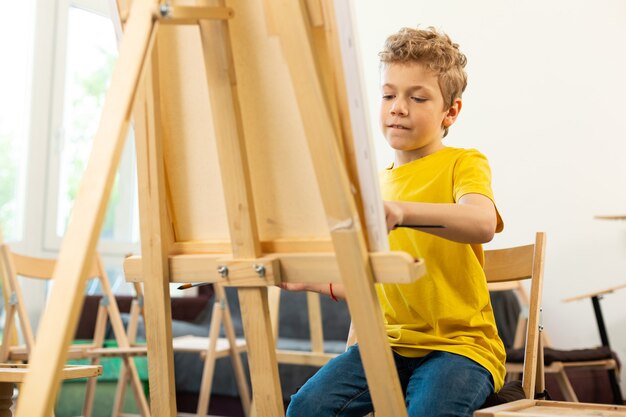 Garoto talentoso se sentindo bem enquanto pinta na escola de arte