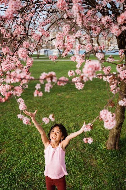 Garoto tentando pegar a linda flor de sakura rosa no parque