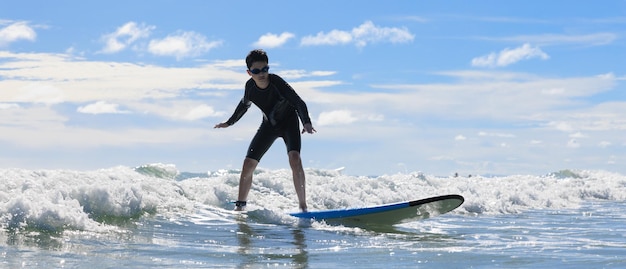 Foto garoto usando óculos de natação estável fica em prancha macia enquanto pratica surf na aula de iniciantes