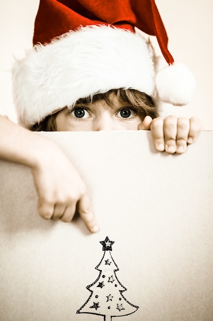 Garoto vestido de Papai Noel com papel em branco. Conceito de férias de natal