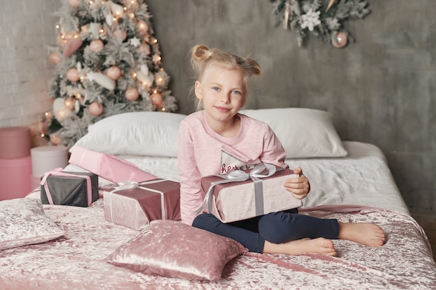 Garoto vestindo pijama e abrindo o presente de Natal