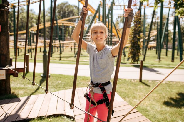 Garotos corajosos em escaladas de equipamento no parque de corda, playground. Crianças subindo na ponte suspensa, esportes radicais de aventura nas férias, entretenimento ao ar livre