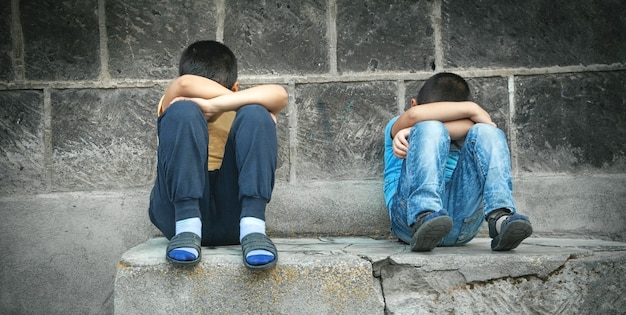 Garotos tristes caucasianos sentados na rua.