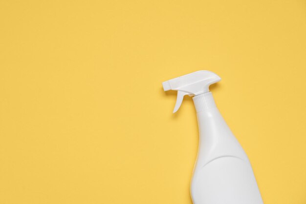 Garrafa branca com líquido de limpeza sobre fundo amarelo