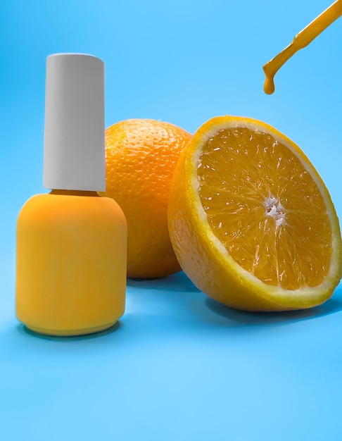 Garrafa brilhante de esmalte em um fundo azul com frutas laranja