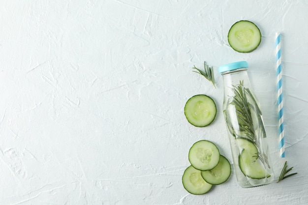 Garrafa com água de pepino infundida em fundo branco, espaço para texto