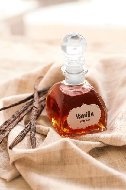 Foto garrafa com extrato aromático e favas de baunilha secas no guardanapo