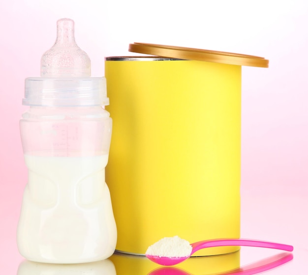 Foto garrafa com leite e comida para bebês em fundo rosa
