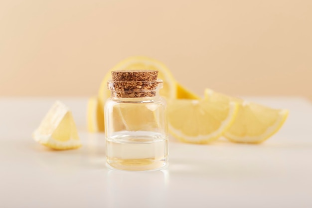 Garrafa com óleo essencial de limão com fatias de limão na mesa Óleo cítrico cosmético ou soro Conceito de medicina natural Aromaterapia