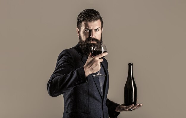 Garrafa copo de vinho tinto Homem de barba barbudo degustação de sommelier Vinho tinto em garrafa copo de vinho Vinho tinto em um copo Sommelier homem degustador vinícola