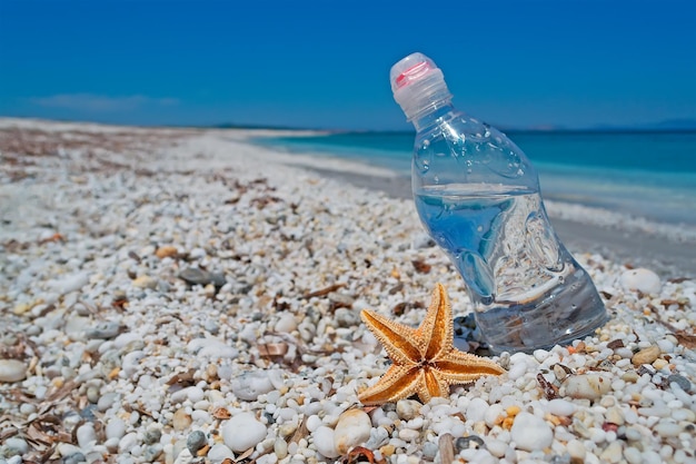 Garrafa de água e estrela do mar em seixos brancos