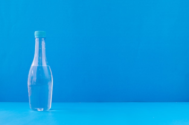 Foto garrafa de água mineral sobre fundo azul.