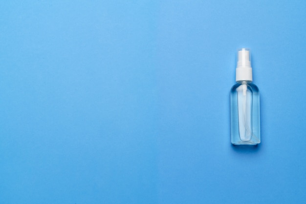 Garrafa de álcool anti-séptico mão higienizar spray sobre um fundo azul para a prevenção de coronavírus - layout plano com espaço da cópia