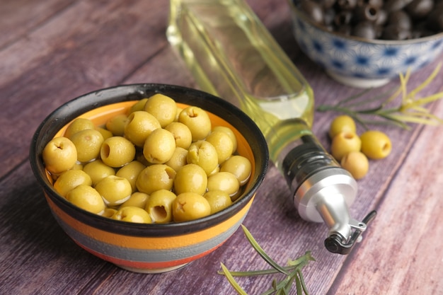 Garrafa de azeite de oliva verde e preta em um recipiente sobre a mesa