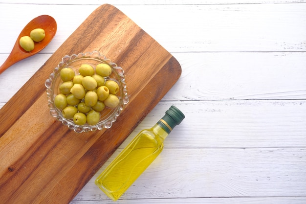 Garrafa de azeite e azeitona fresca em um recipiente na mesa